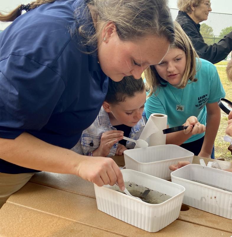 Jackie Toggart of Envirotech Environmental Consulting examines critters with the help of Addie Baich, center, and Emma Rowley.